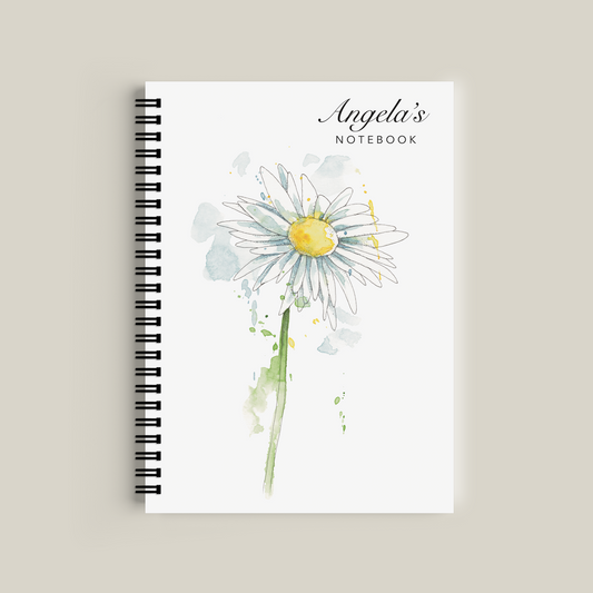 Notebook with a daisy design and 'Angela's Notebook' text on a beige background