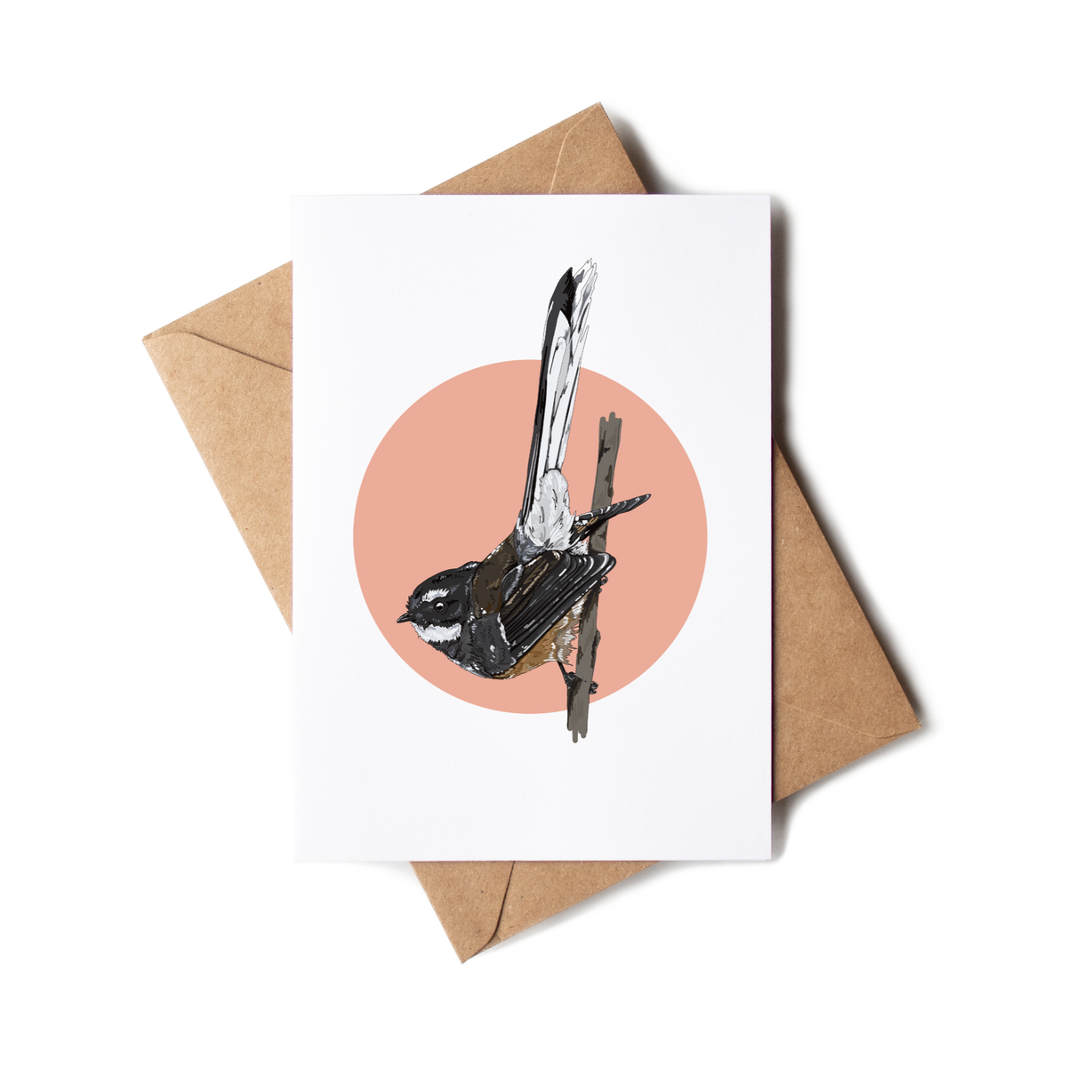 Greeting card with a bird illustration on a pink circle, placed on a white surface with a brown envelope.