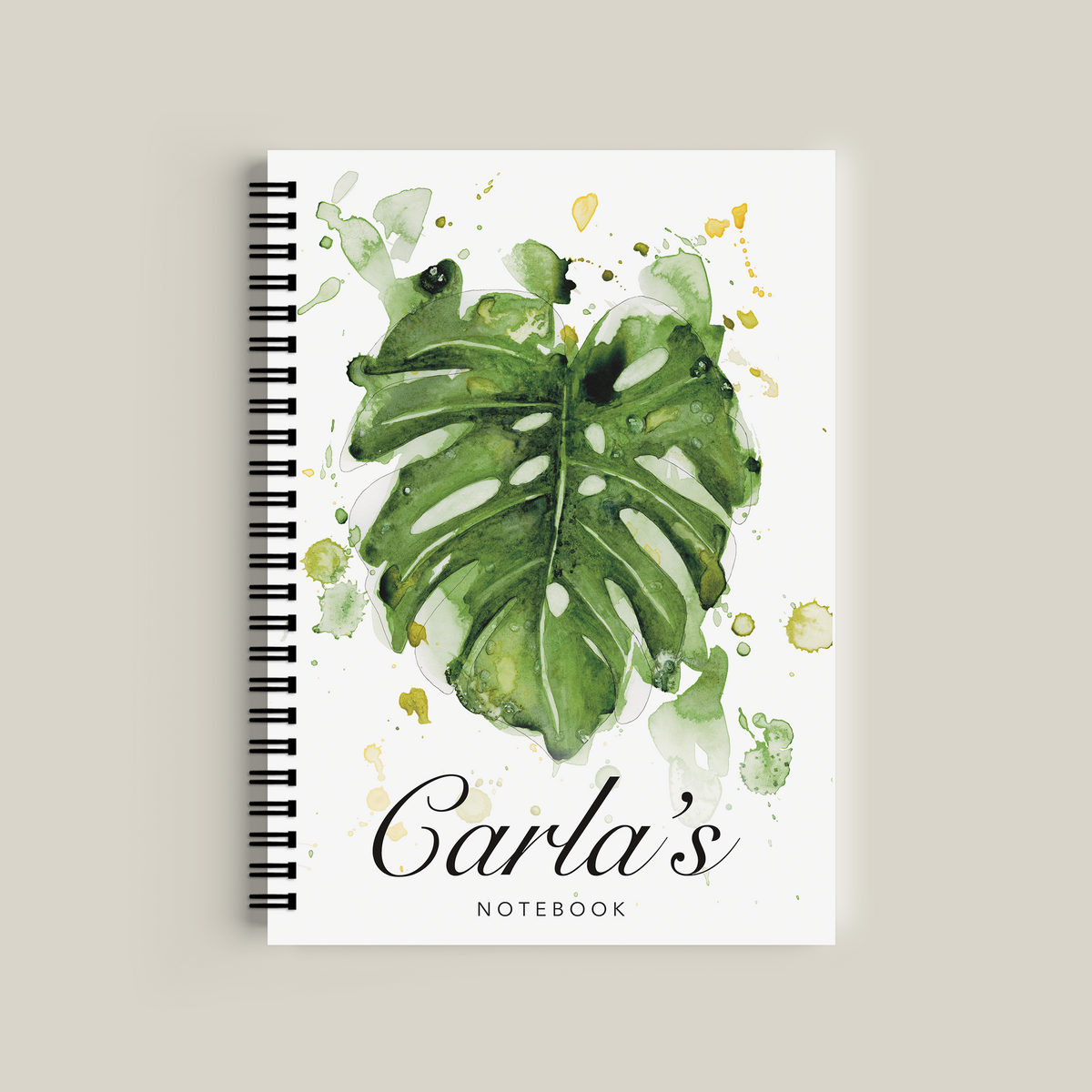 Notebook with green leaf design and 'Carla's Notebook' text on a beige background