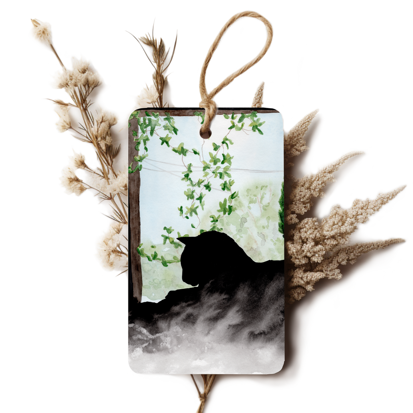 Decorative tag with a black cat silhouette and greenery, surrounded by dried plants on a white background.