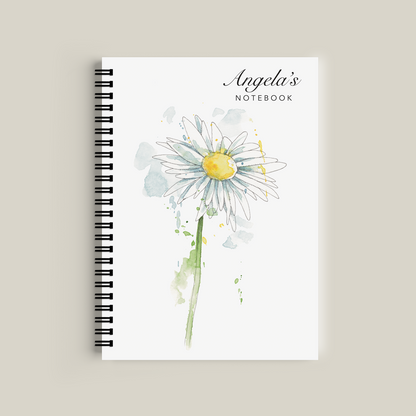 Notebook with a daisy design and 'Angela's Notebook' text on a beige background