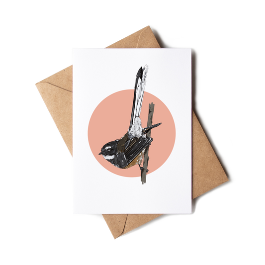 Greeting card with a bird illustration on a pink circle, placed on a white surface with a brown envelope.