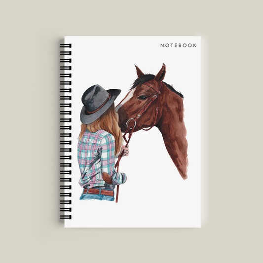Notebook with a design of a person in a hat and plaid shirt petting a horse on a white background