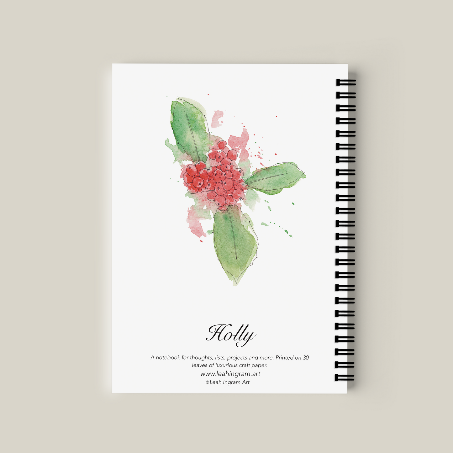 Notebook with holly design on cover against a beige background