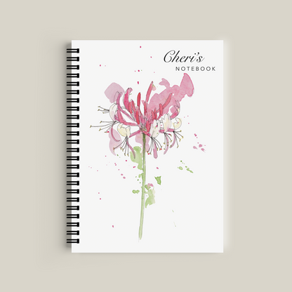 Notebook with floral design and 'Cheri's' branding on a beige background