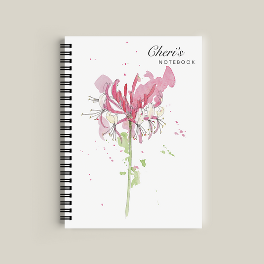 Notebook with floral design and 'Cheri's' branding on a beige background