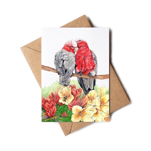 Greeting card with two parrots on a branch and flowers, accompanied by a brown envelope.