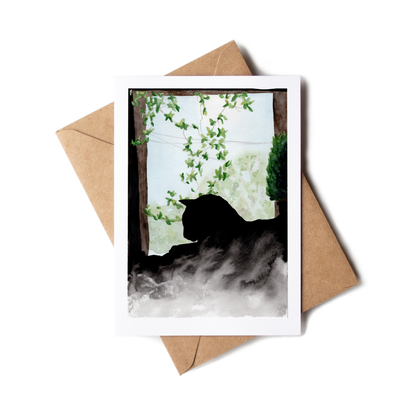 Greeting card with a cat silhouette and floral design, placed on a brown envelope.