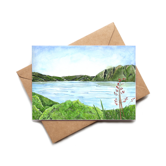 Greeting card with a scenic illustration of a lake and mountains, placed on a brown envelope.