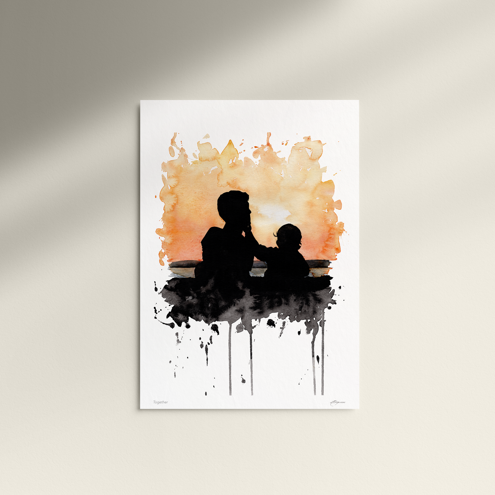 Art print of a silhouette of a father and child against an abstract watercolor background on a white wall.