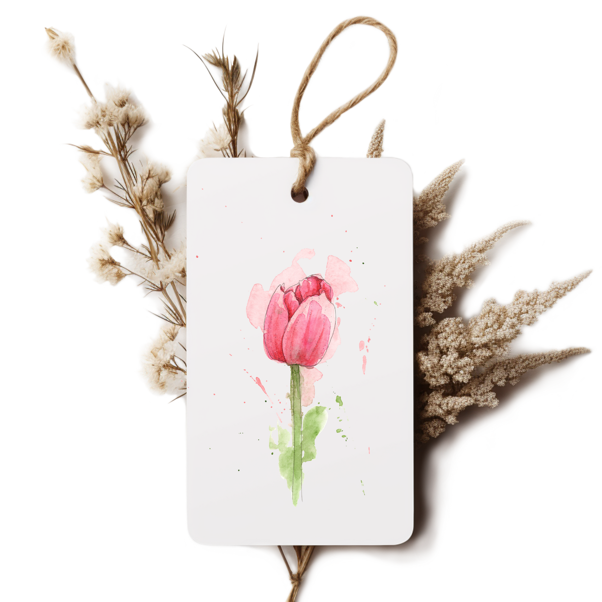 White tag with pink tulip design surrounded by dried flowers on a white background