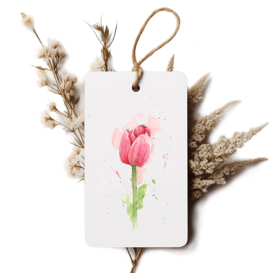 White tag with pink tulip design surrounded by dried flowers on a white background