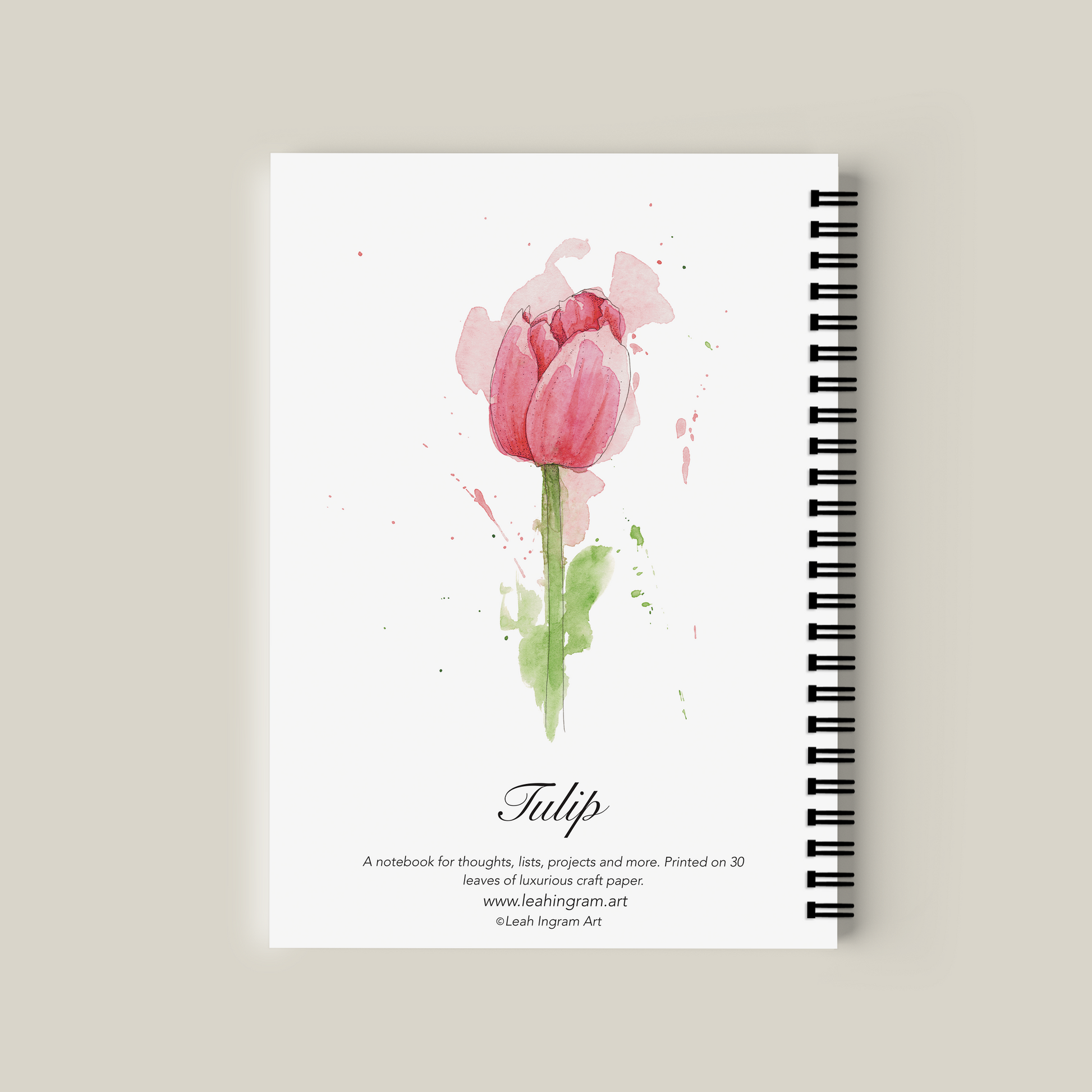 Notebook with a pink tulip design on the cover against a beige background