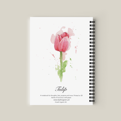 Notebook with a pink tulip design on the cover against a beige background