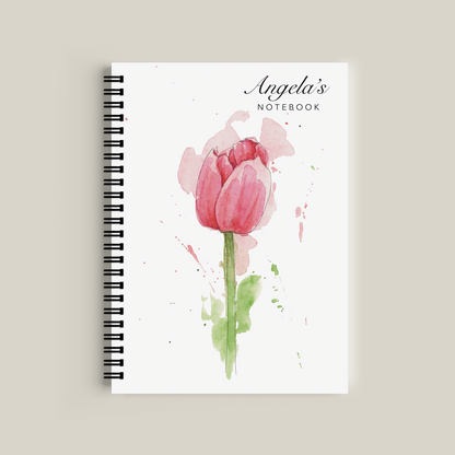 Notebook with a pink tulip design on the cover against a beige background
