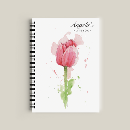 Notebook with a pink tulip design on the cover against a beige background